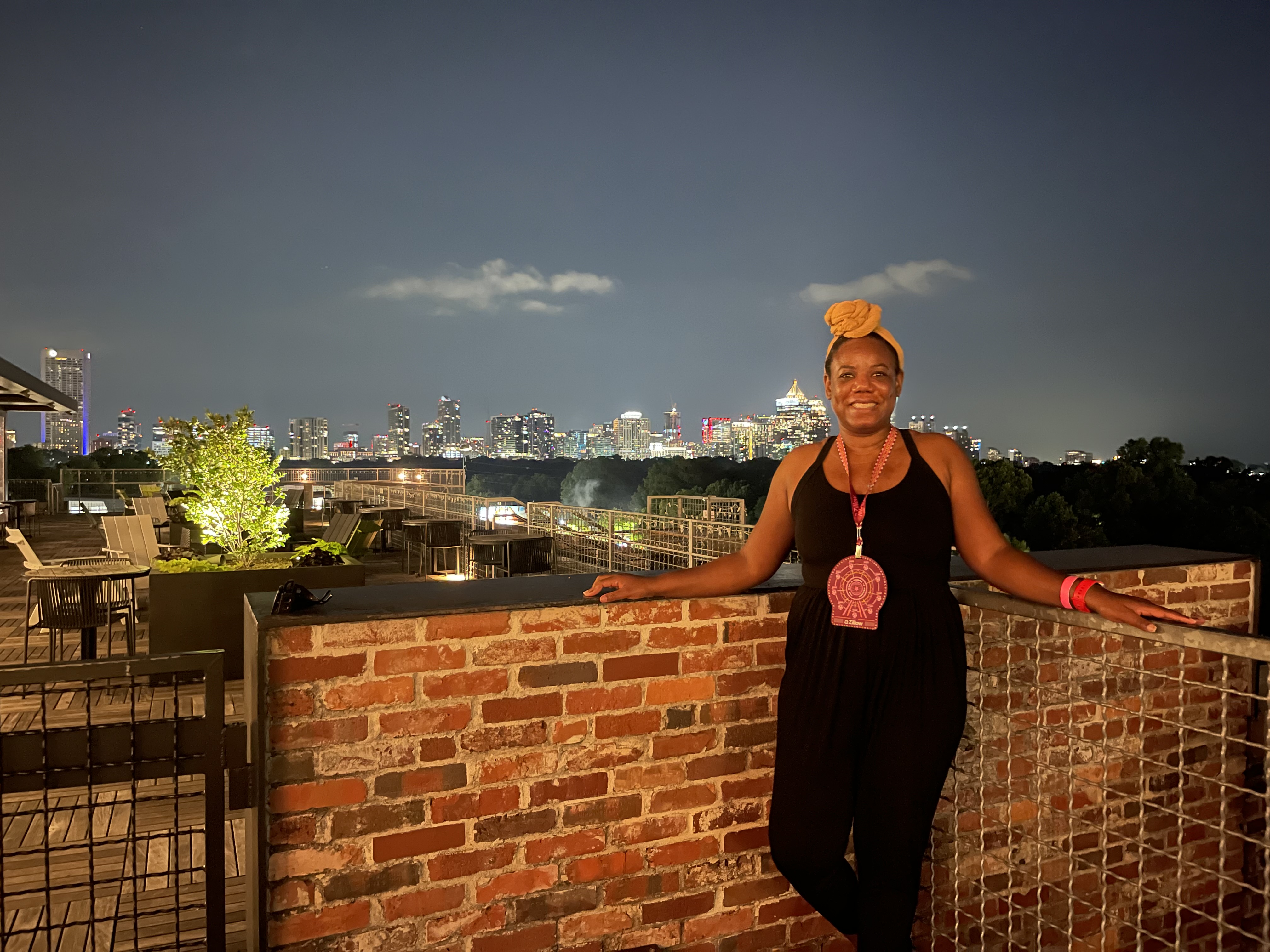 Nikema Prophet on a rooftop at night with the city skyline behind her